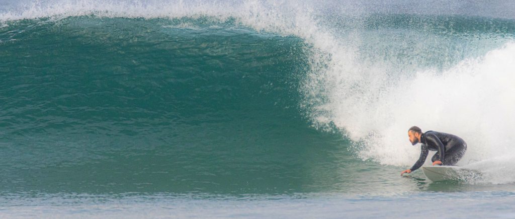 surfer riding wave at ponzos beach, galicia, winter