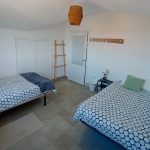 Bright twin bedroom with two beds, wardrobe, and minimalist decor at Nordés Surfhouse Ferrol Galicia